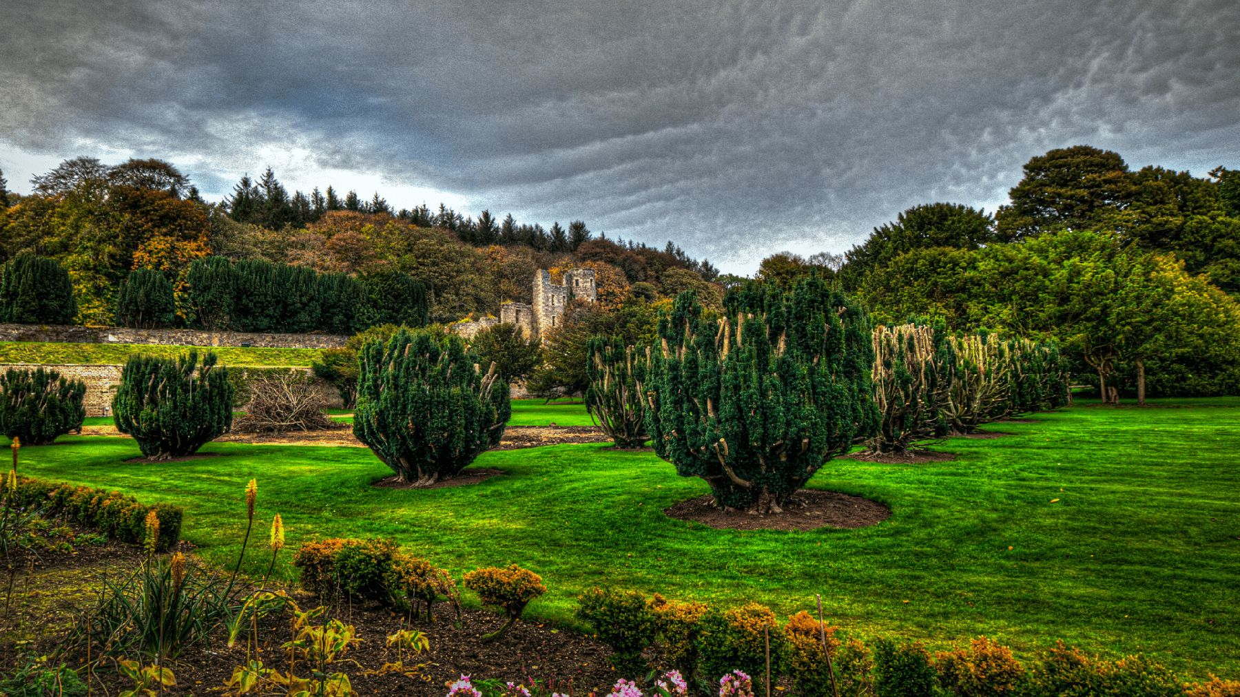 A long view across the mown lawns and clipped shrubs of the walled garden