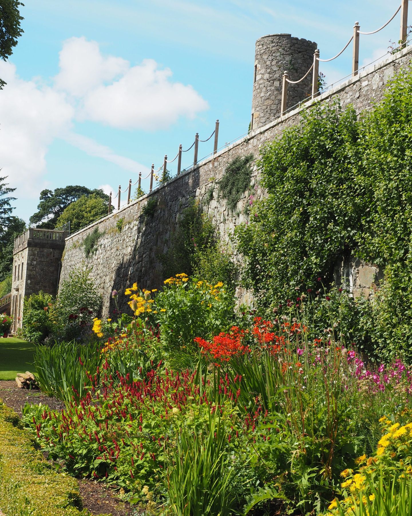 The high stone terrace wall with borders planted at its foot